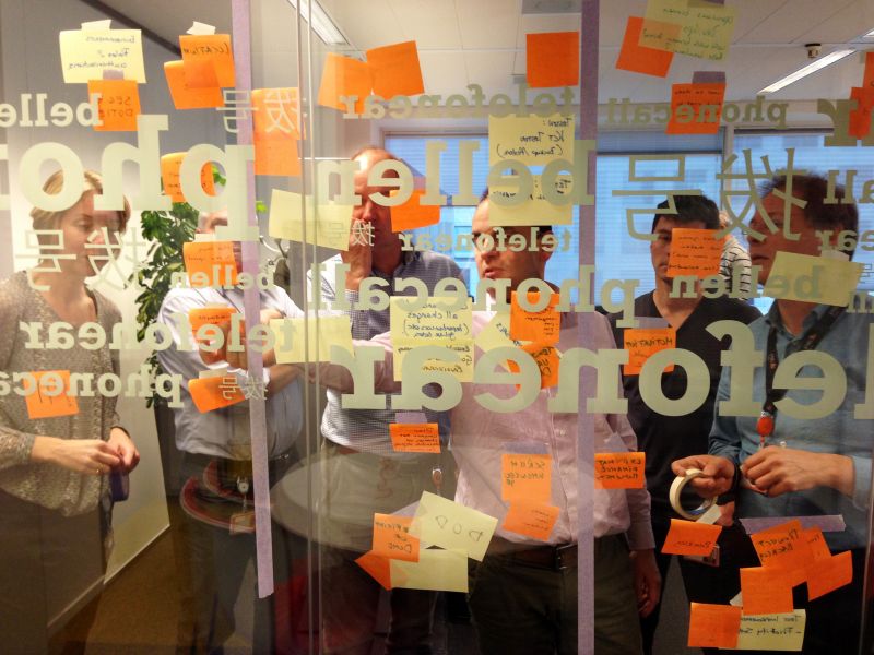 Workshop participants with sticky notes on a glass wall